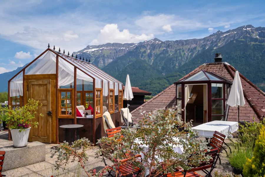 Glaspavillon auf der Dachterrasse im Sommer, dahinter die Berge