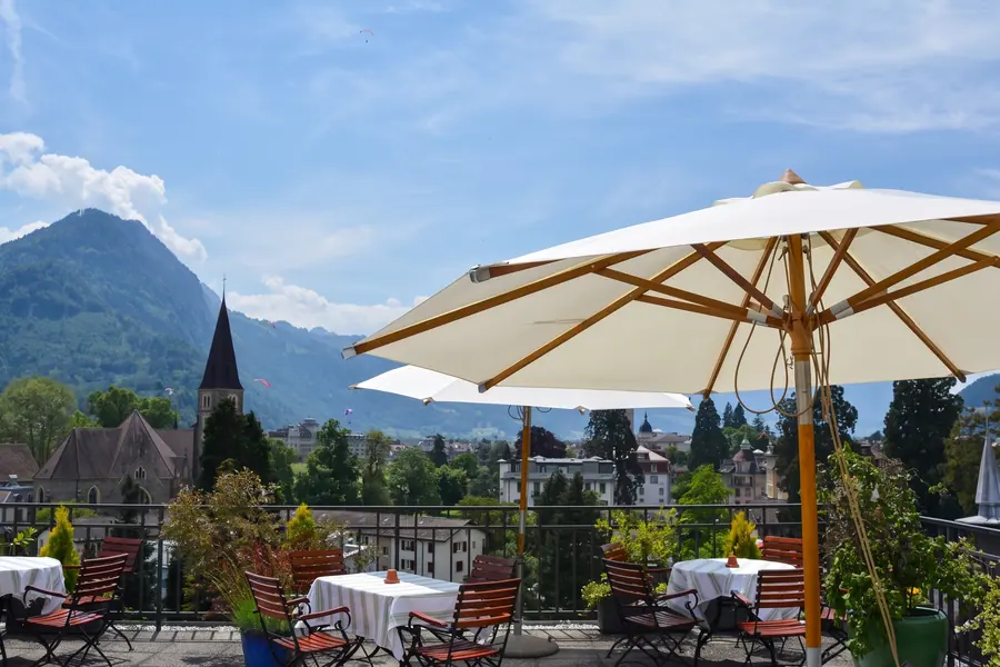 Dachterrasse mit Sonnenschirm, dahinter die Berge