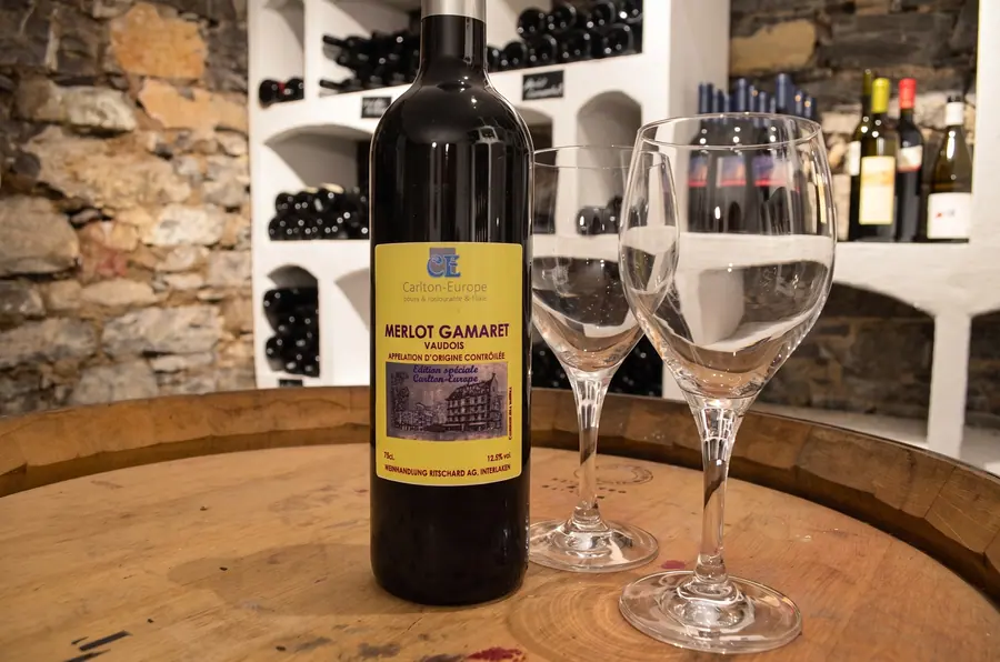 Flasche Merlot Gamaret mit zwei Gläsern auf dem Fass