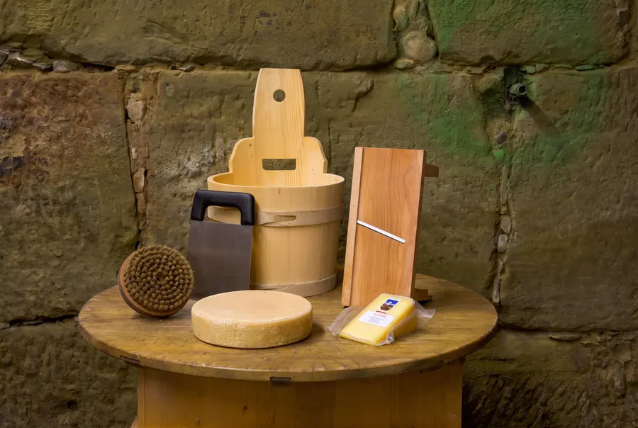 Meule de fromage, rabot à fromage et ustensiles en bois dans la cave à fromages