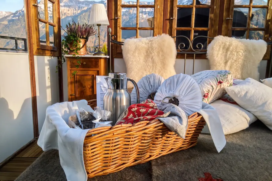 Frühstückskorb im Glaspavillon, dahinter die verschneiten Berge