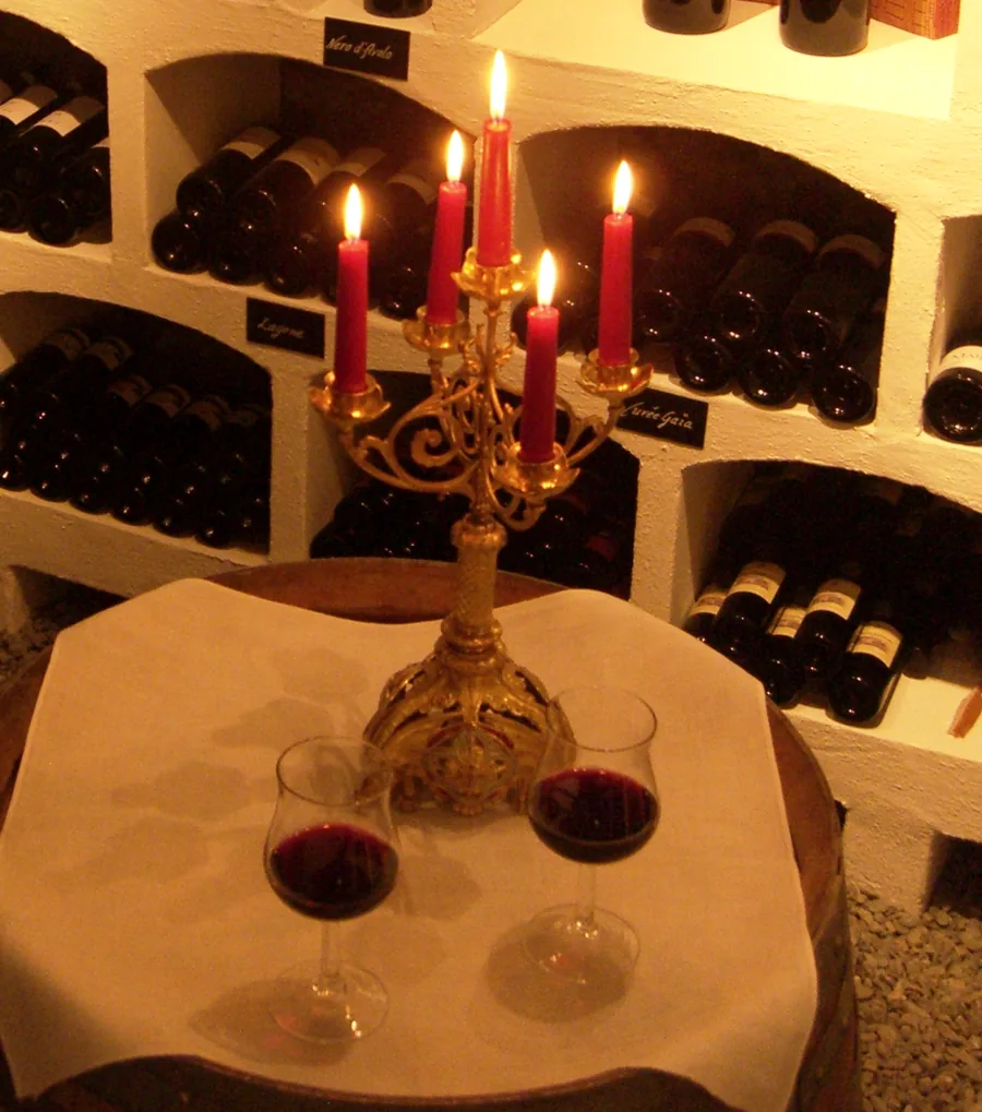 Brennende Kerzen und zwei Gläser Rotwein im Gewölbekeller